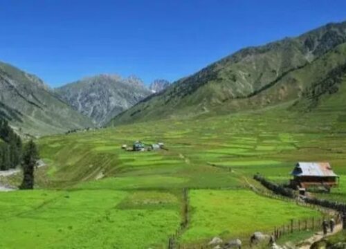 A remote valley surrounded by lofty peaks and lush green meadows.